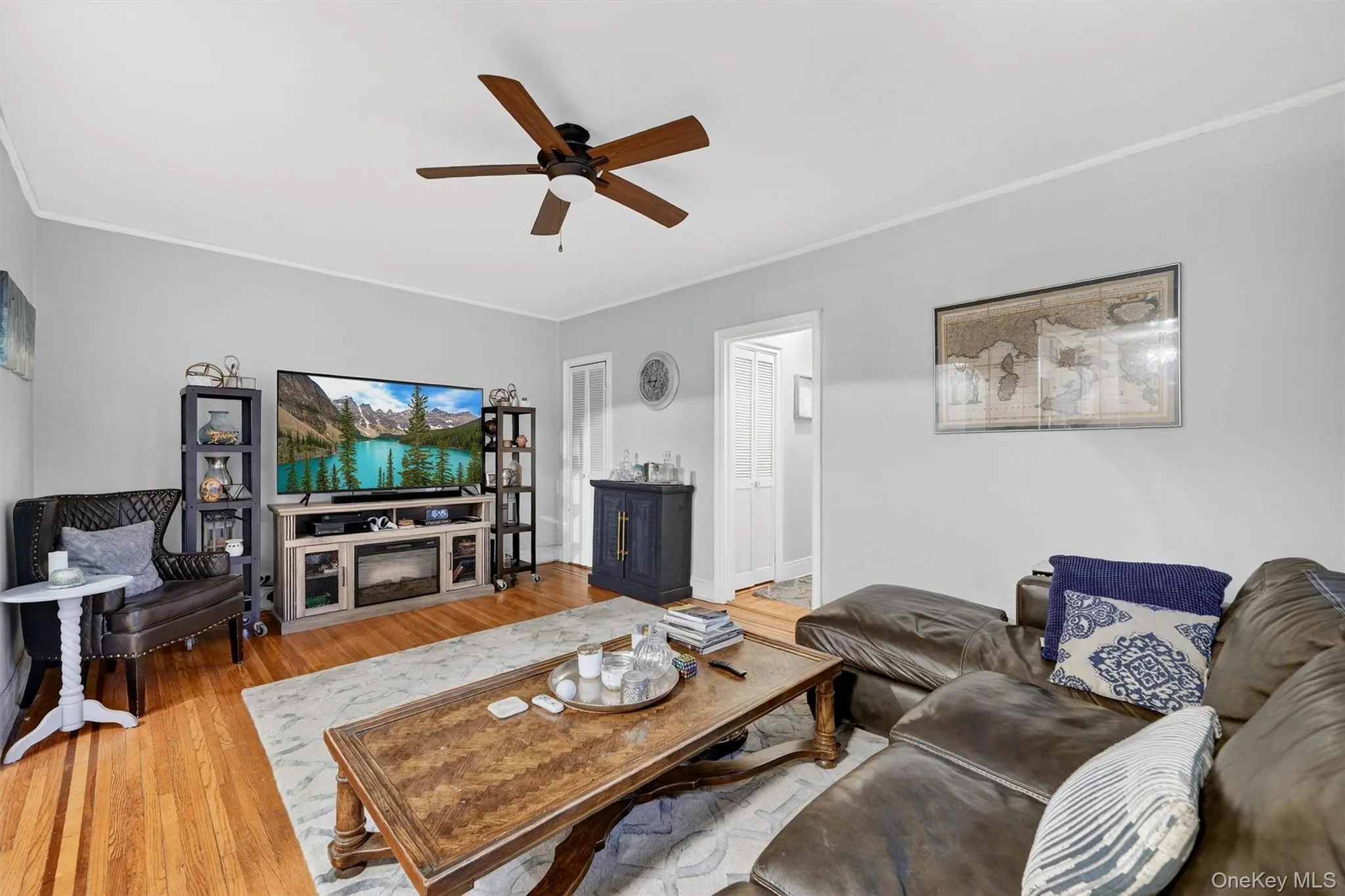 Living area with wood finished floors, a ceiling fan, and crown molding Living area with wood finished floors, a ceiling fan, and crown molding