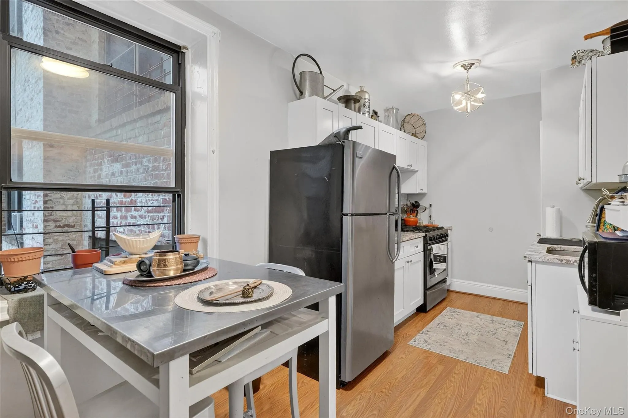 Kitchen featuring plenty of natural light, light stone countertops, stainless steel appliances, and white cabinets Kitchen featuring plenty of natural light, light stone countertops, stainless steel appliances, and white cabinets