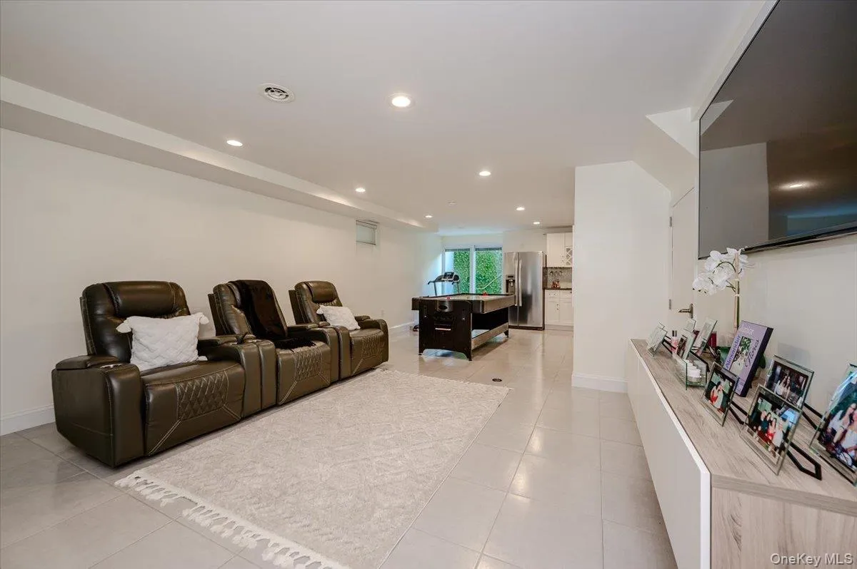 Spacious open-concept lower level with recessed lighting, tile flooring, and a media wall Spacious open-concept lower level with recessed lighting, tile flooring, and a media wall