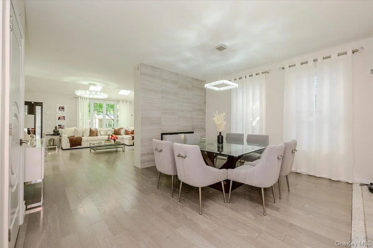 Wood-finish flooring throughout, modern square chandelier, and a feature wall with horizontal paneling Wood-finish flooring throughout, modern square chandelier, and a feature wall with horizontal paneling