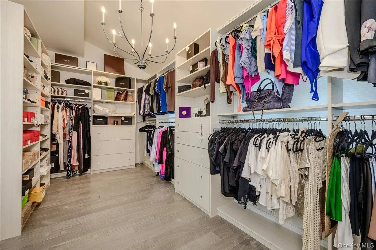 Custom closet system featuring extensive shelving, built-in drawer units, multiple hanging rods, and wood-finish flooring Custom closet system featuring extensive shelving, built-in drawer units, multiple hanging rods, and wood-finish flooring