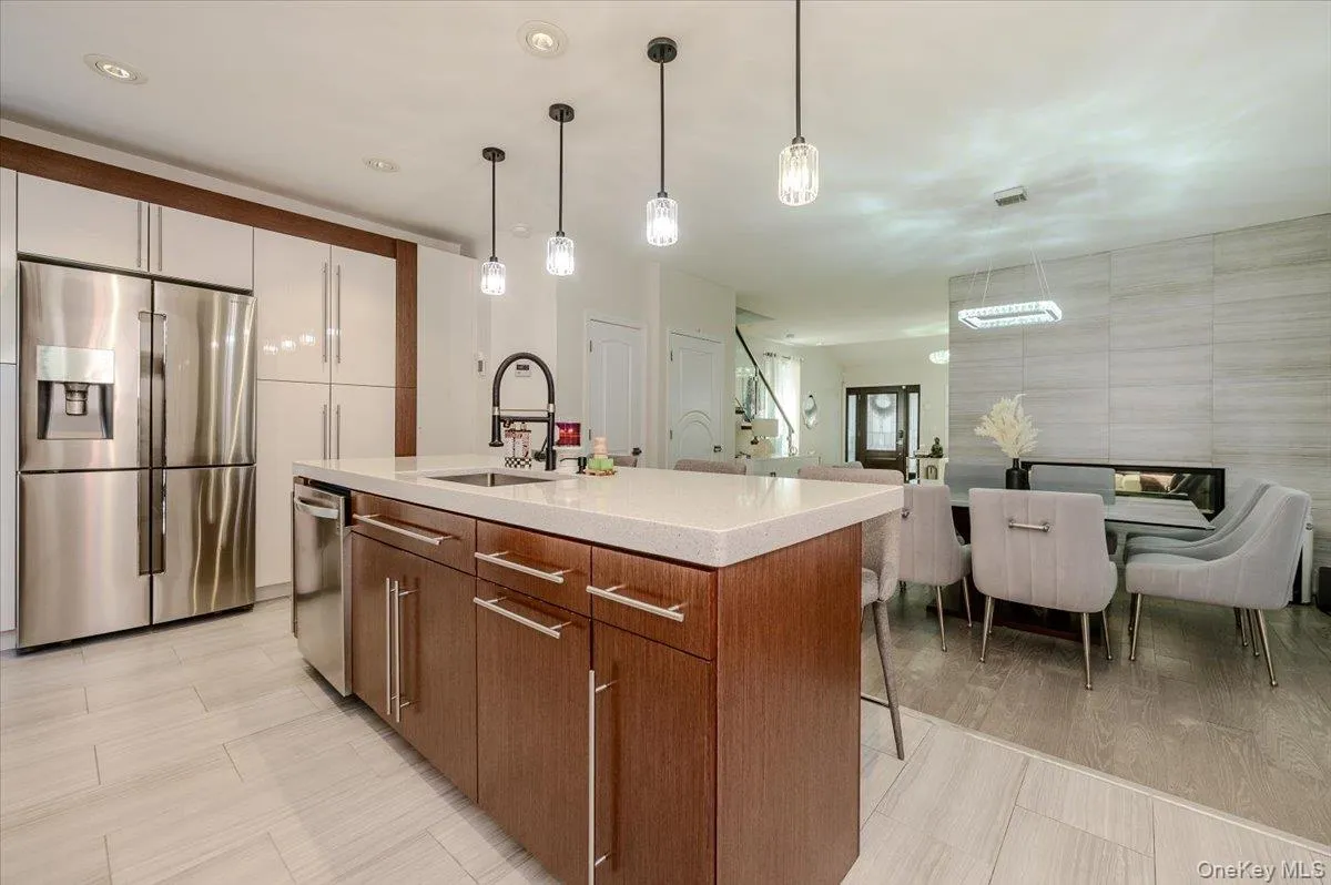 Kitchen featuring a stainless steel refrigerator, wood-finish cabinetry, and a center island with a sink Kitchen featuring a stainless steel refrigerator, wood-finish cabinetry, and a center island with a sink