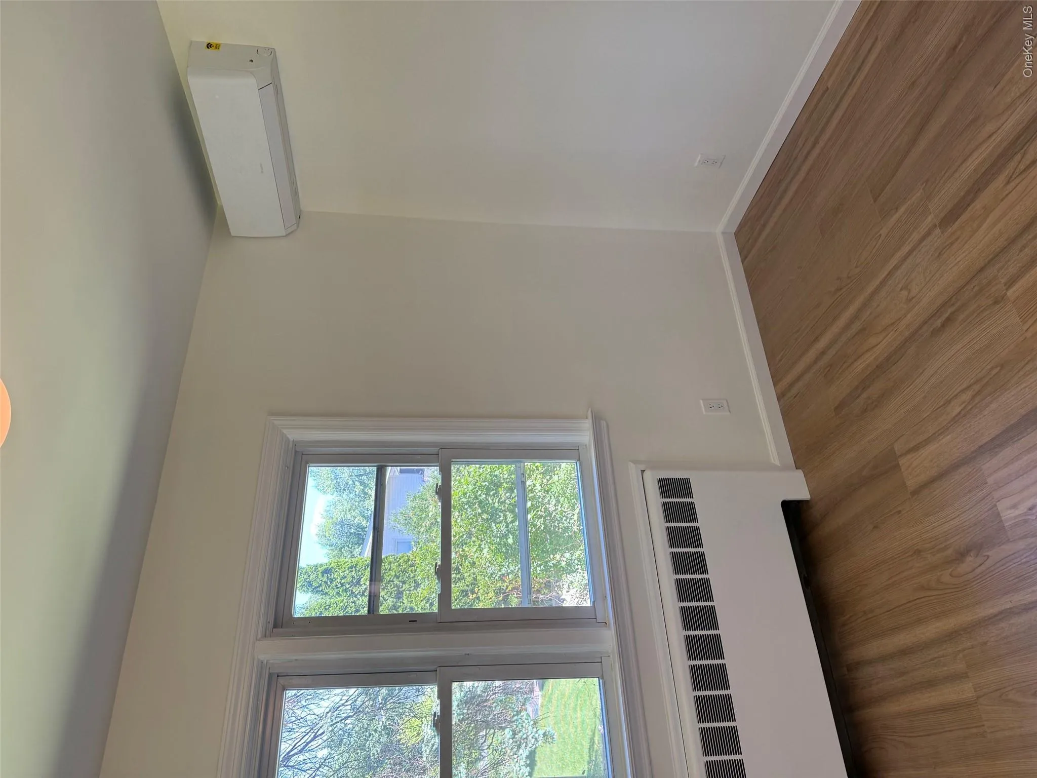 Spare room with a wall unit AC, radiator heating unit, wood finished floors, and baseboards Spare room with a wall unit AC, radiator heating unit, wood finished floors, and baseboards