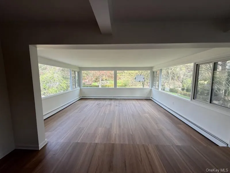 Unfurnished sunroom featuring a baseboard heating unit, wood finished floors, and plenty of natural light Unfurnished sunroom featuring a baseboard heating unit, wood finished floors, and plenty of natural light