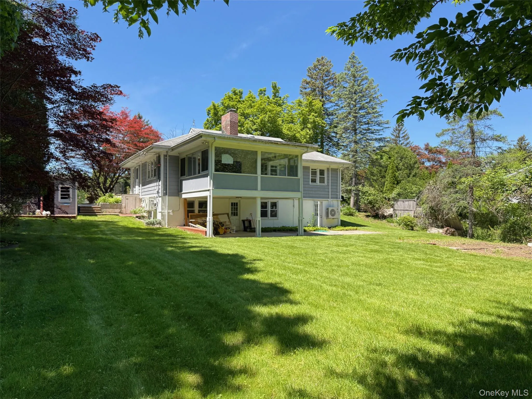 Back of house with a sunroom, a chimney, and a yard Back of house with a sunroom, a chimney, and a yard