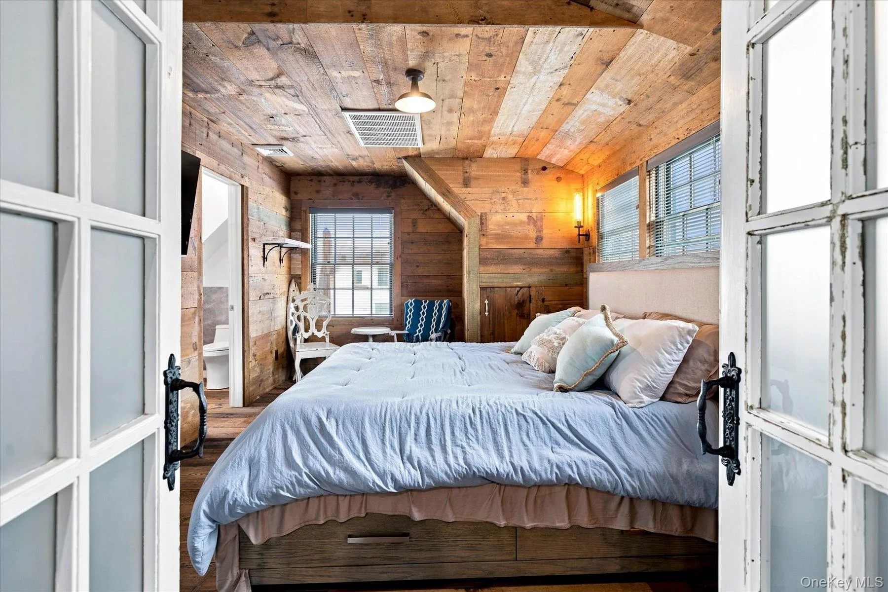 Primary bedroom with reclaimed wood-paneled walls and ceiling Primary bedroom with reclaimed wood-paneled walls and ceiling