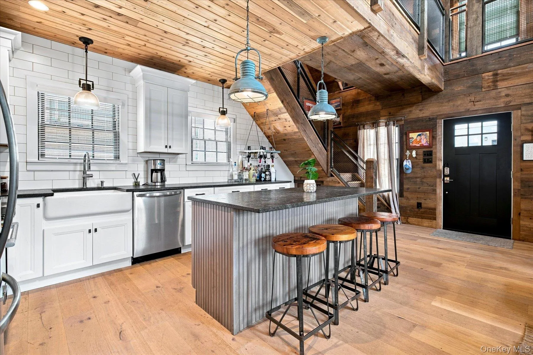 Hardwood flooring throughout, white shaker cabinetry, subway tile backsplash, stainless steel appliances, and a wood-paneled ceiling Hardwood flooring throughout, white shaker cabinetry, subway tile backsplash, stainless steel appliances, and a wood-paneled ceiling