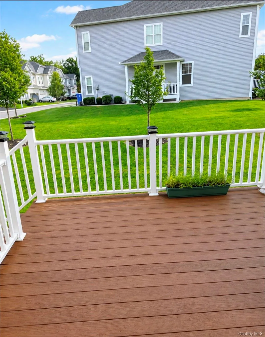 Spacious deck with wood-finish flooring, white railing, and exterior lighting Spacious deck with wood-finish flooring, white railing, and exterior lighting