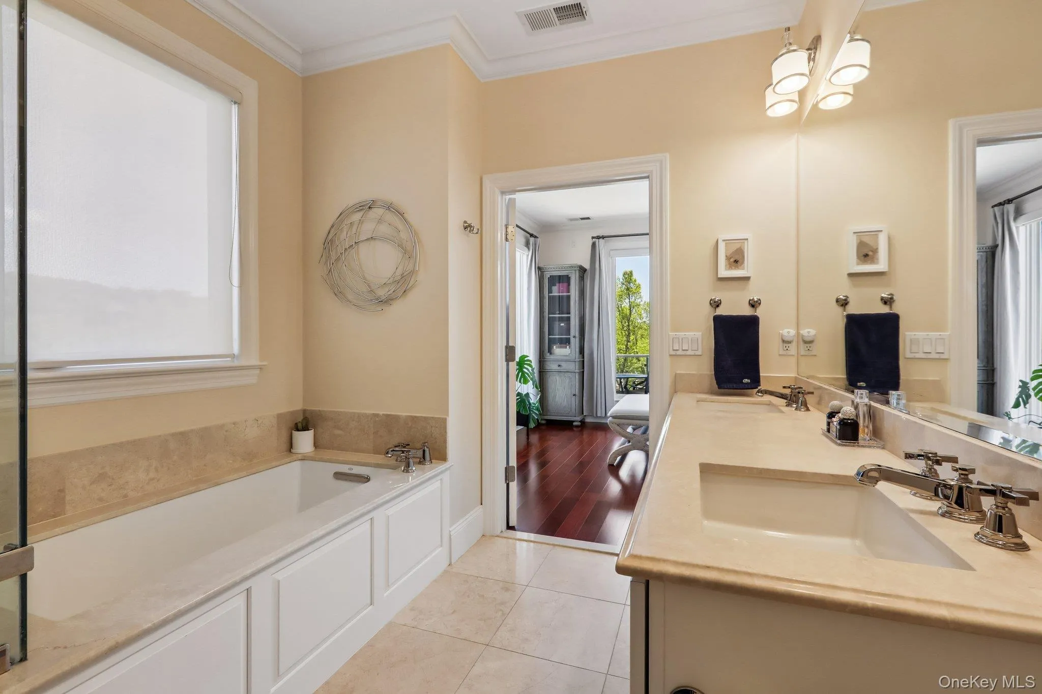 Spacious bathroom featuring a built-in soaking tub, dual vanity with undermount sinks, stone countertops, and tile flooring Spacious bathroom featuring a built-in soaking tub, dual vanity with undermount sinks, stone countertops, and tile flooring