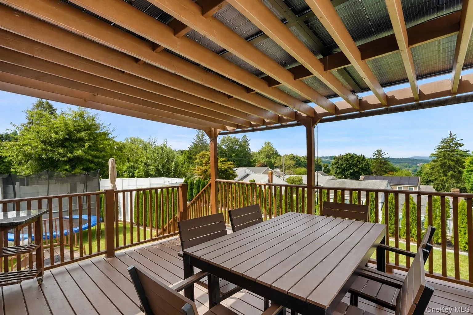 Multi-level wood-finish deck with integrated pergola, privacy railing, and built-in staircase Multi-level wood-finish deck with integrated pergola, privacy railing, and built-in staircase