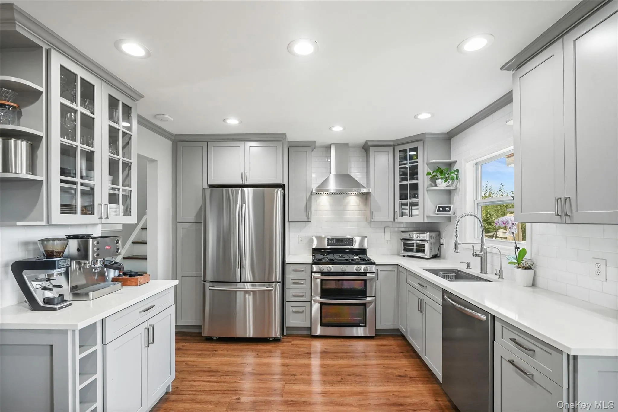 Recessed lighting, wood-finish flooring, light gray cabinetry, stainless steel appliances, and quartz countertops Recessed lighting, wood-finish flooring, light gray cabinetry, stainless steel appliances, and quartz countertops