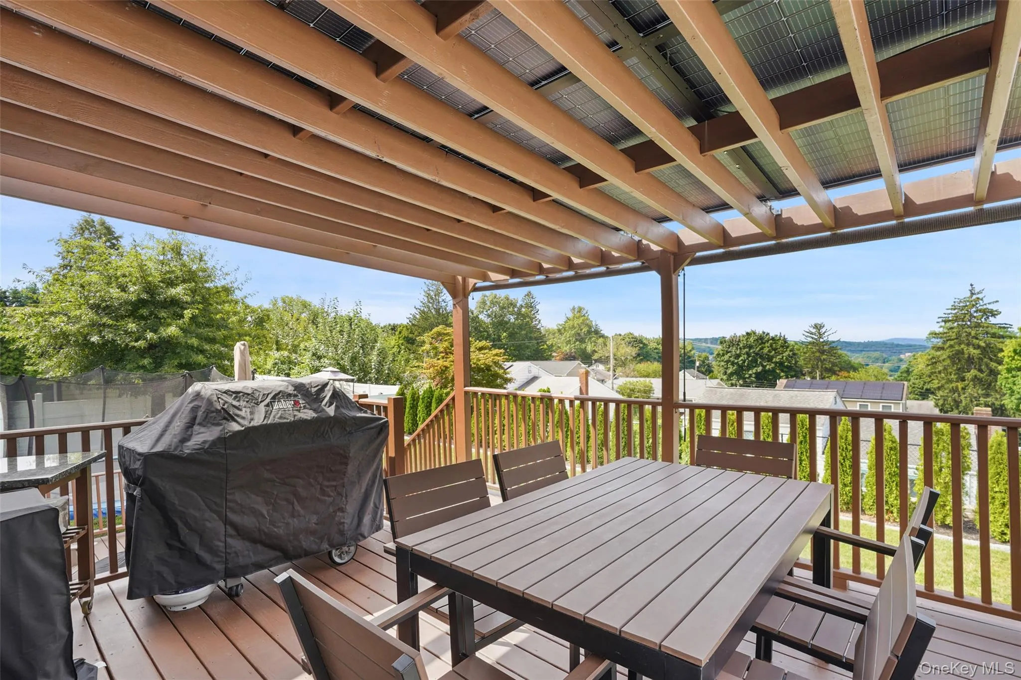 Multi-level wood-finish deck with integrated pergola, privacy railing, and built-in staircase Multi-level wood-finish deck with integrated pergola, privacy railing, and built-in staircase