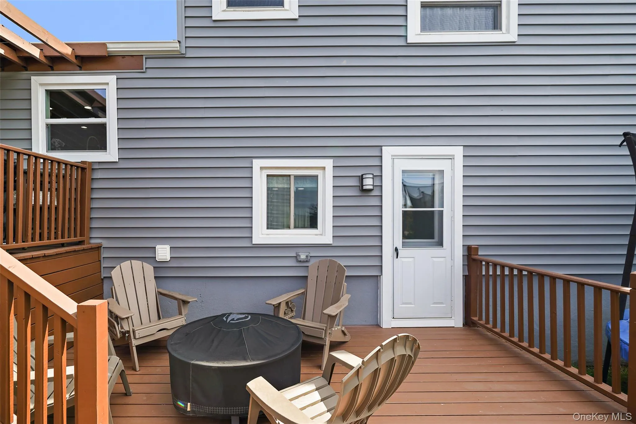 Multi-level wood-finish deck with integrated pergola, privacy railing, and built-in staircase Multi-level wood-finish deck with integrated pergola, privacy railing, and built-in staircase
