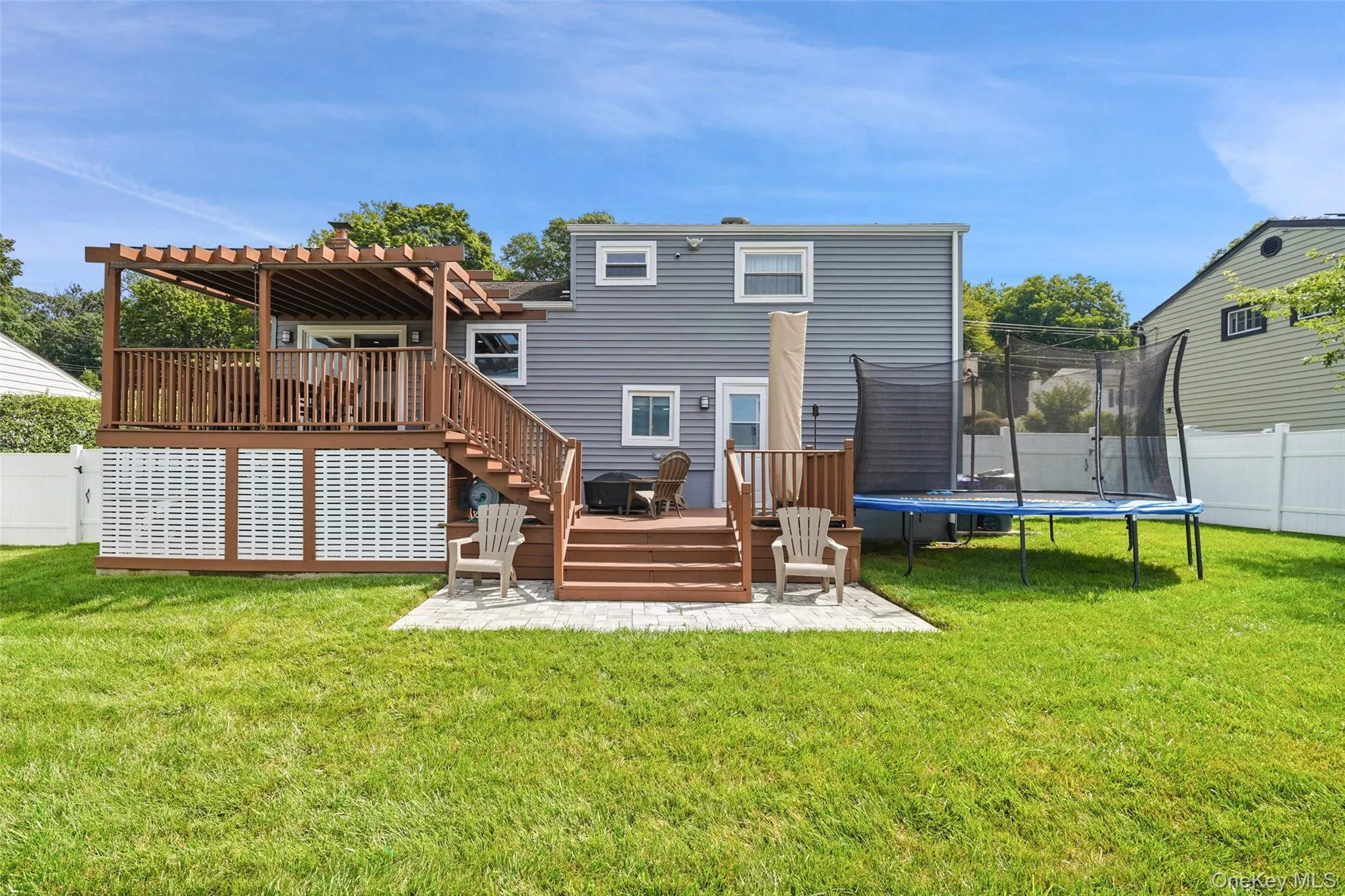 Multi-level wood-finish deck with pergola, lower patio area, and vinyl siding Multi-level wood-finish deck with pergola, lower patio area, and vinyl siding