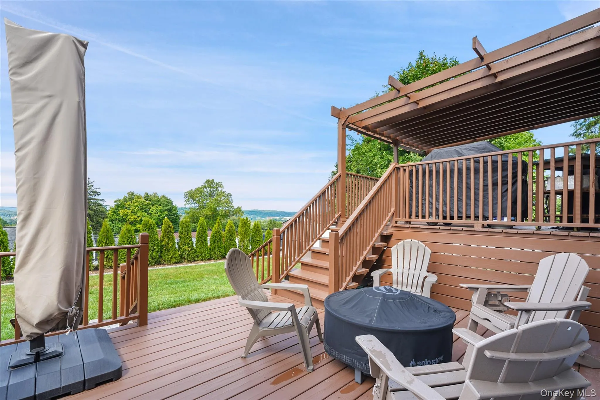 Multi-level wood-finish deck with integrated pergola, privacy railing, and built-in staircase Multi-level wood-finish deck with integrated pergola, privacy railing, and built-in staircase