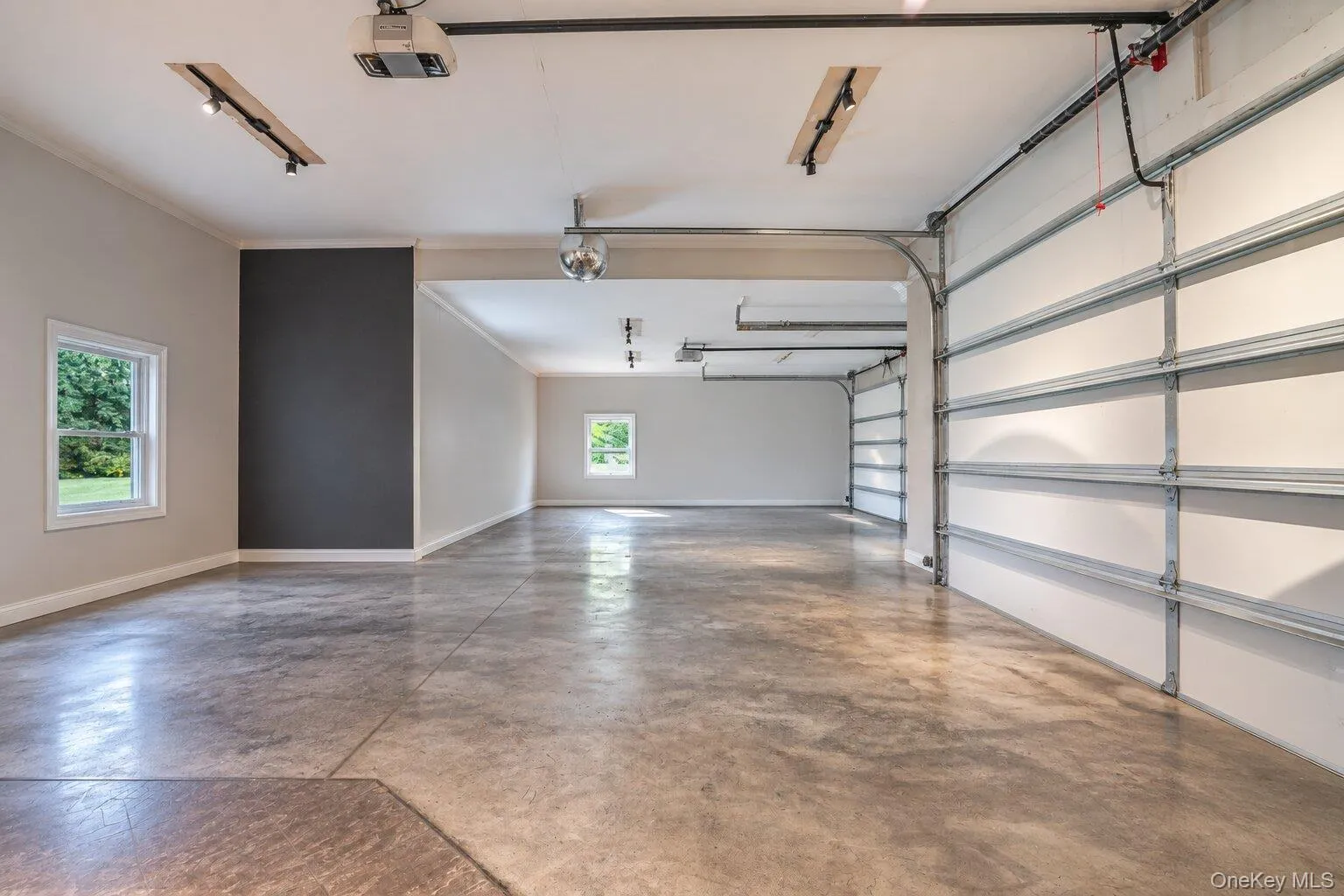 4 bay garage featuring a concrete floor, track lighting, and a window - decluttered with aI 4 bay garage featuring a concrete floor, track lighting, and a window - decluttered with aI