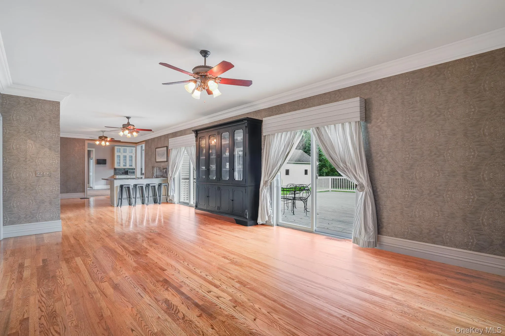 Hardwood flooring, crown molding, patterned wall covering, recessed lighting, and a sliding glass door. Hardwood flooring, crown molding, patterned wall covering, recessed lighting, and a sliding glass door.