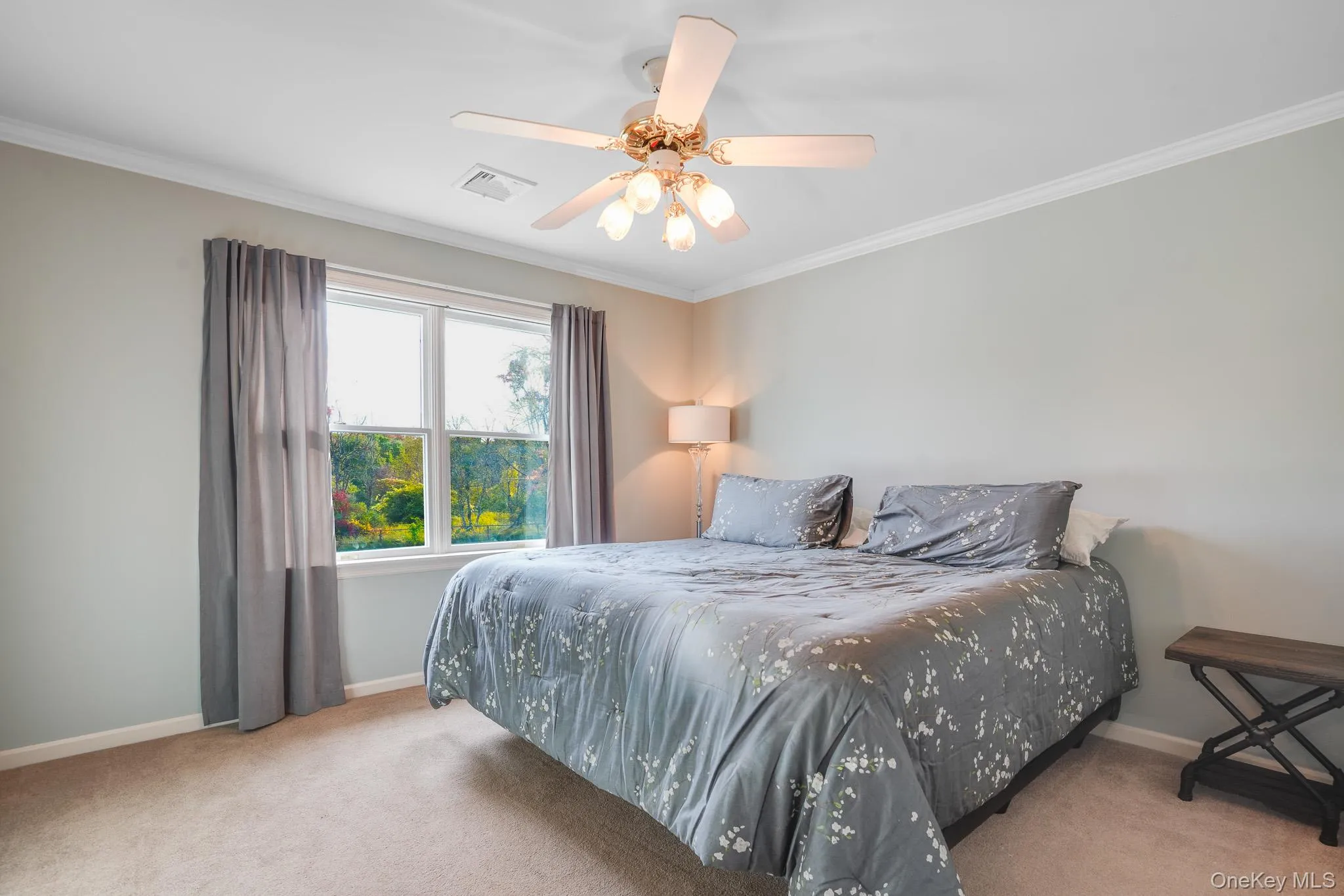 Bedroom with light-toned wall finishes, crown molding, and a ceiling fan with integrated lighting. Bedroom with light-toned wall finishes, crown molding, and a ceiling fan with integrated lighting.