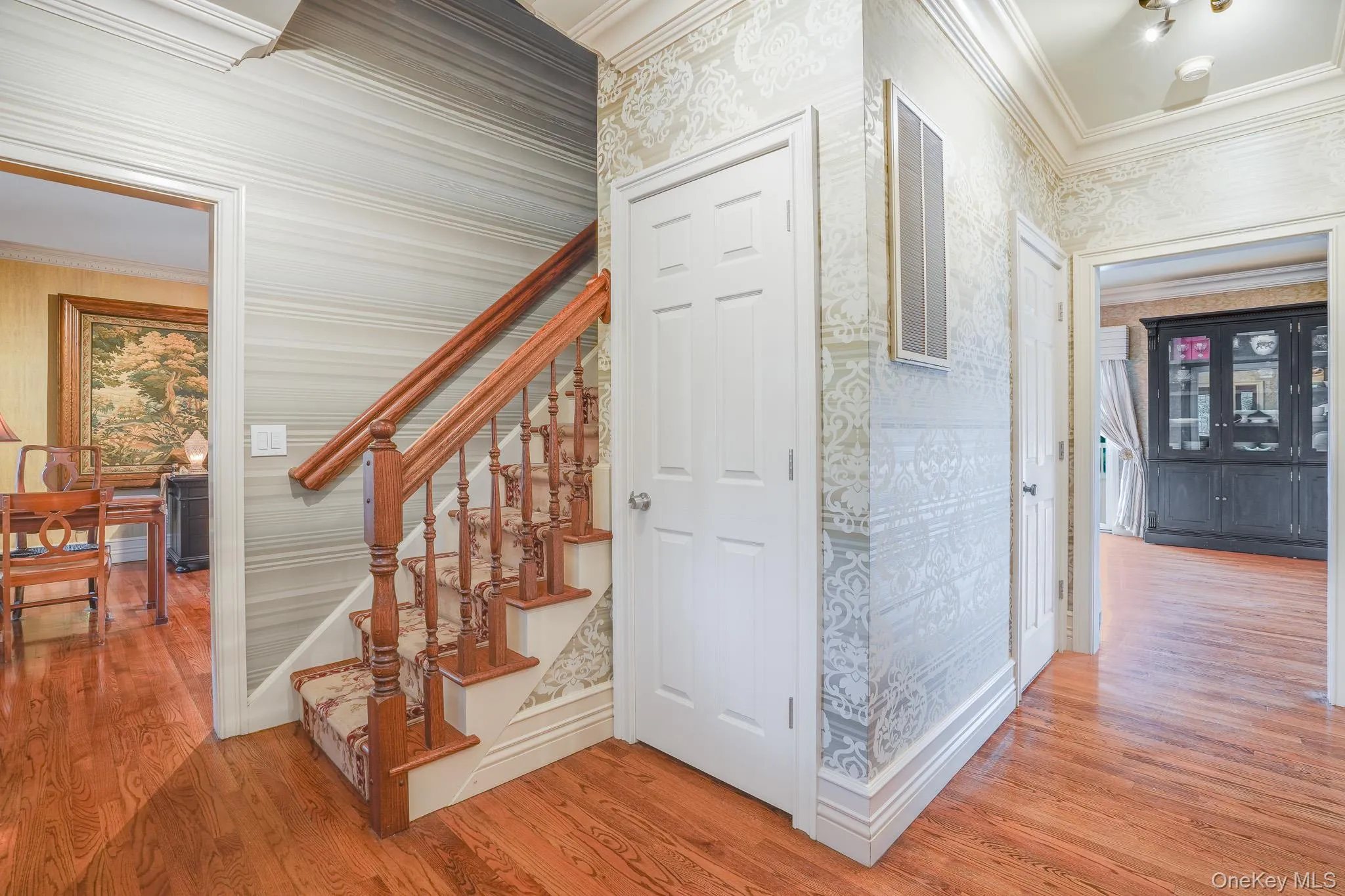 Entry Foyer with hardwood flooring, decorative wallpaper, substantial wood staircase, crown molding, leading to the rest of the home. Entry Foyer with hardwood flooring, decorative wallpaper, substantial wood staircase, crown molding, leading to the rest of the home.
