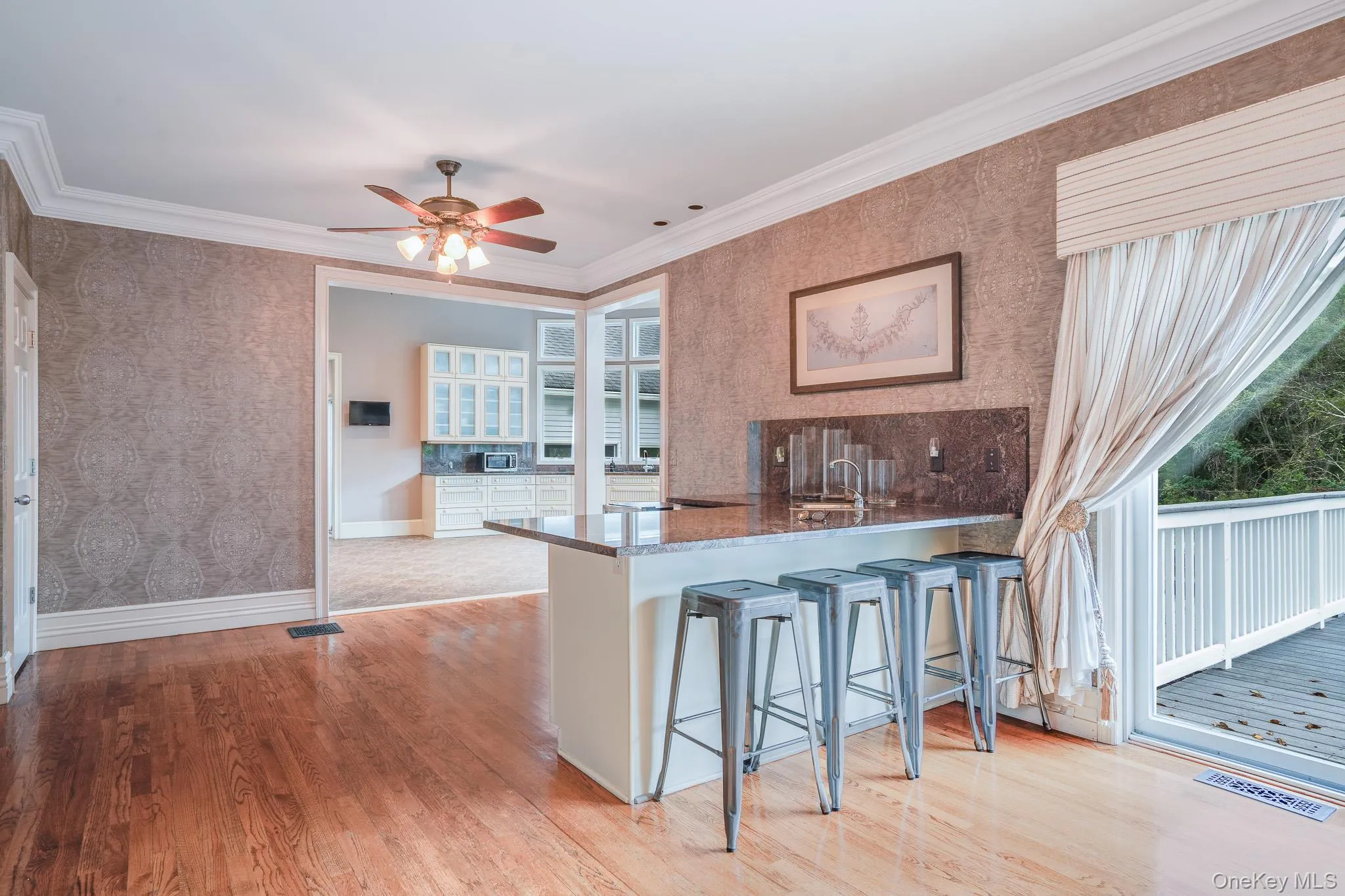 Wet bar with hardwood flooring, patterned wallpaper, recessed lighting, looking into the chef's kitchen and the deck. Wet bar with hardwood flooring, patterned wallpaper, recessed lighting, looking into the chef's kitchen and the deck.