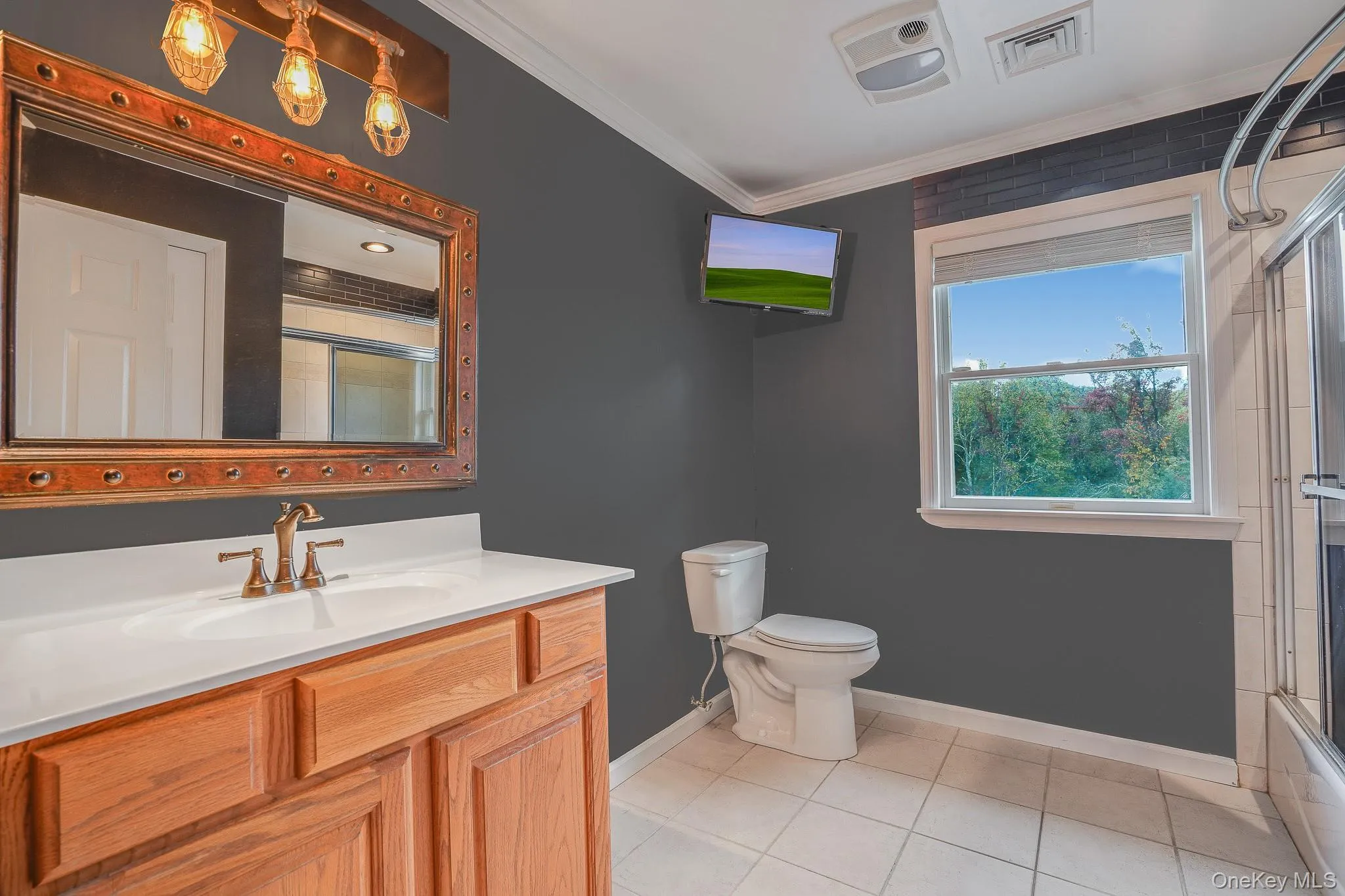 Full bathroom wood-finish vanity with an integrated sink, bronze-finish faucet and toilet. Full bathroom wood-finish vanity with an integrated sink, bronze-finish faucet and toilet.
