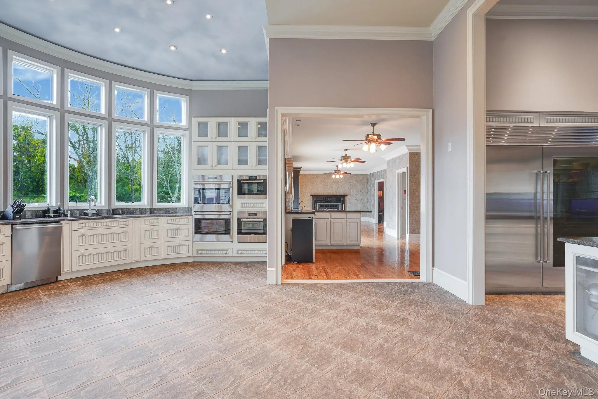 Chef's kitchen with stainless steel appliances, built-in double ovens, white cabinetry, dark countertops, and tile flooring. Chef's kitchen with stainless steel appliances, built-in double ovens, white cabinetry, dark countertops, and tile flooring.