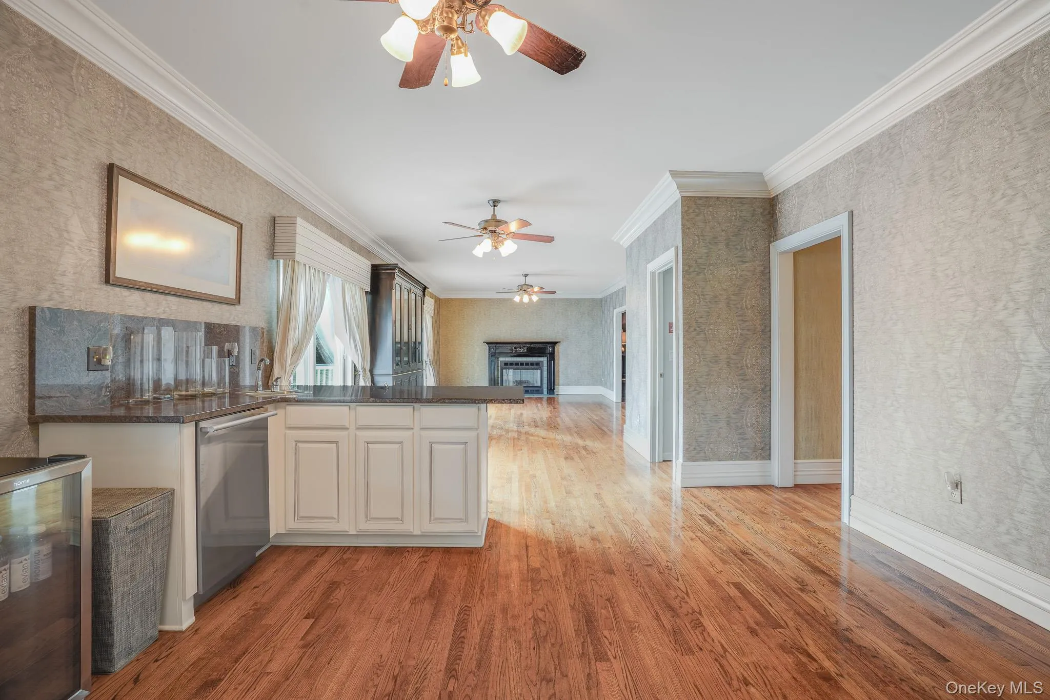 Open concept living area featuring hardowod flooring, a built-in wet bar with a stone countertop, a fireplace, and multiple ceiling fans. Open concept living area featuring hardowod flooring, a built-in wet bar with a stone countertop, a fireplace, and multiple ceiling fans.
