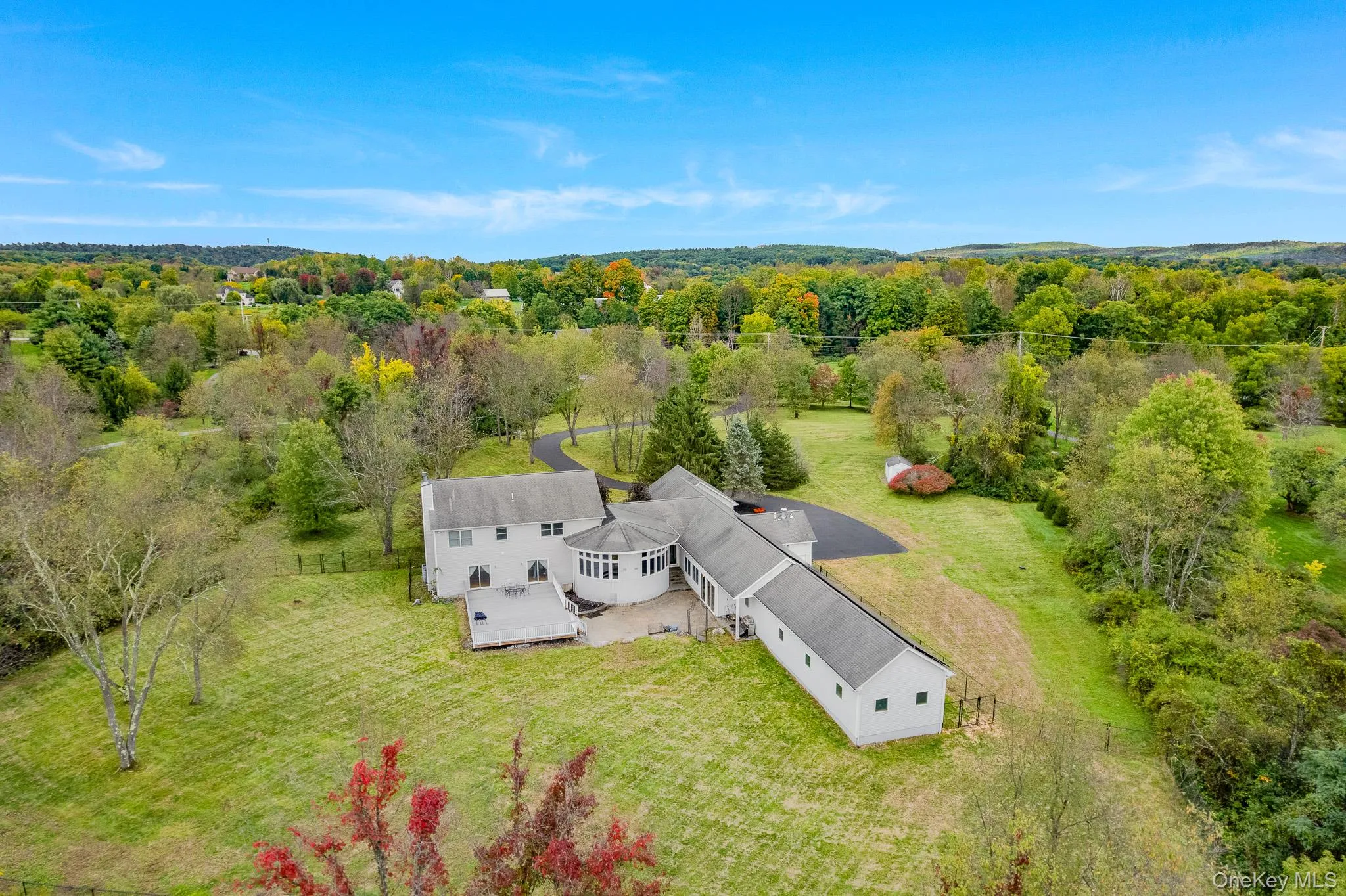 Expansive property featuring a multi-level residence, a circular driveway, a detached shed, a spacious patio, and surrounding natural foliage. Expansive property featuring a multi-level residence, a circular driveway, a detached shed, a spacious patio, and surrounding natural foliage.