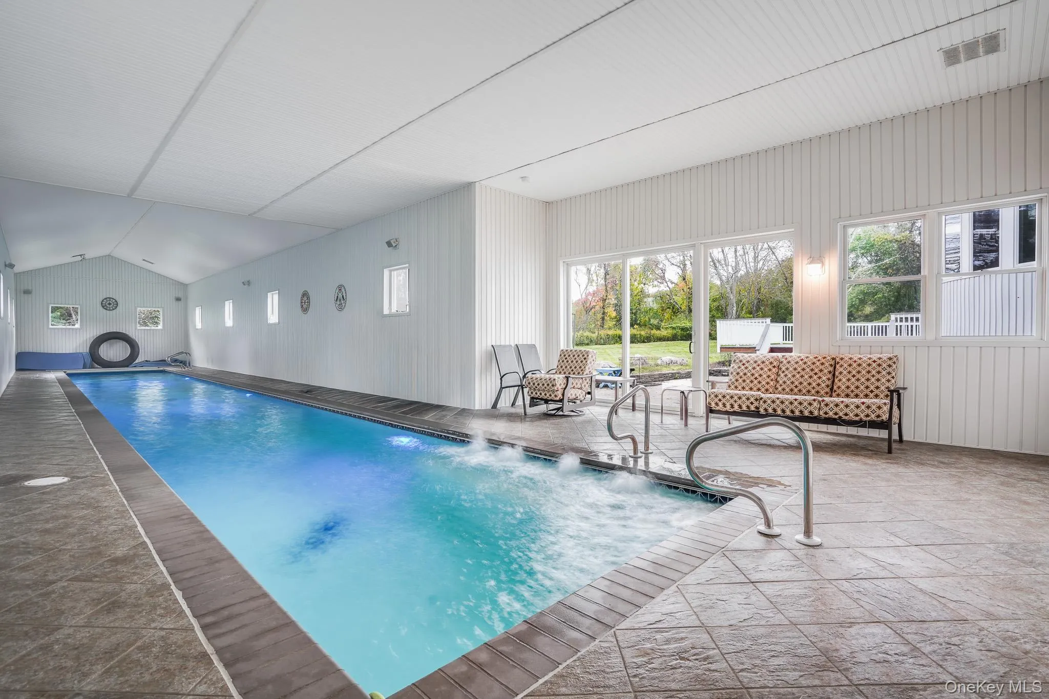 Indoor 75 foot lap pool with integrated spa, tile surround, vaulted ceiling, and sliding glass doors to the exterior Indoor 75 foot lap pool with integrated spa, tile surround, vaulted ceiling, and sliding glass doors to the exterior