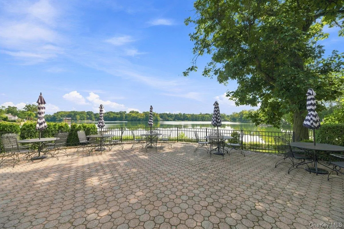 Beautiful, shared patio area with seating, umbrellas, and serene lake views. Beautiful, shared patio area with seating, umbrellas, and serene lake views.
