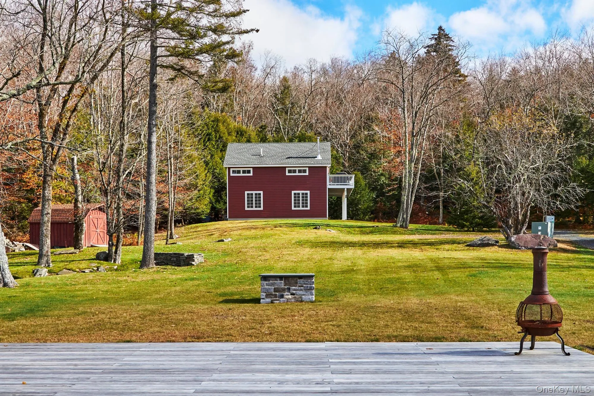 View of green lawn featuring a storage shed, a wooded view, and a fire pit View of green lawn featuring a storage shed, a wooded view, and a fire pit
