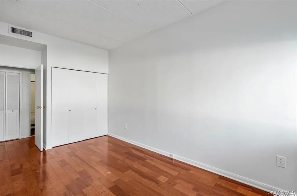 Bedroom with Hardwood flooring and white walls with closet Bedroom with Hardwood flooring and white walls with closet