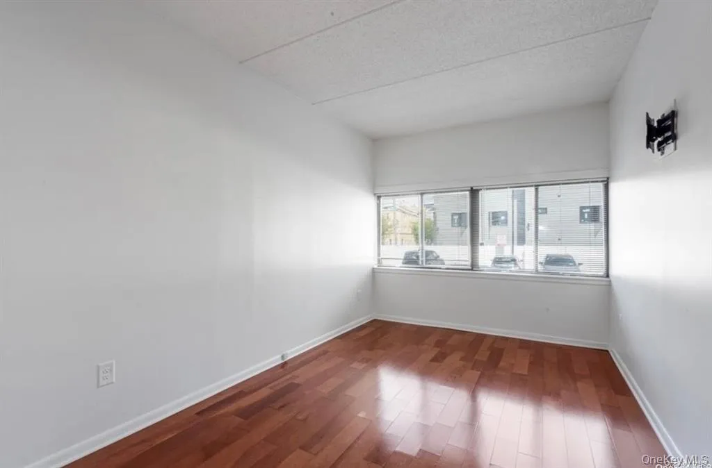 Bedroom with Wood-finish flooring, white walls, and a large window Bedroom with Wood-finish flooring, white walls, and a large window