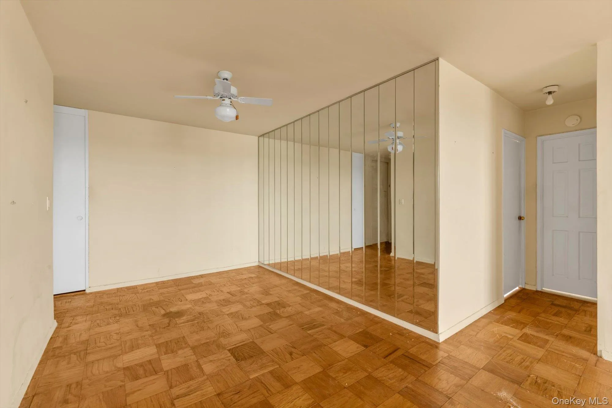 Parquet wood-finish flooring, full-height mirrored wall panels, ceiling fan with integrated lighting, and flush-mount ceiling lighting Parquet wood-finish flooring, full-height mirrored wall panels, ceiling fan with integrated lighting, and flush-mount ceiling lighting