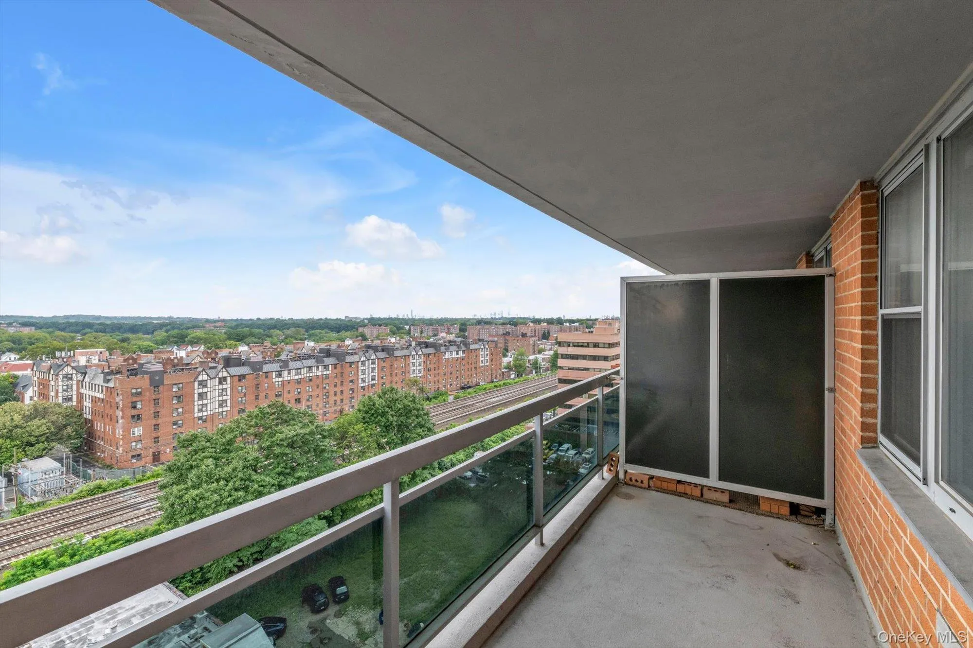 Private balcony with concrete flooring, glass railing, and brick exterior wall Private balcony with concrete flooring, glass railing, and brick exterior wall