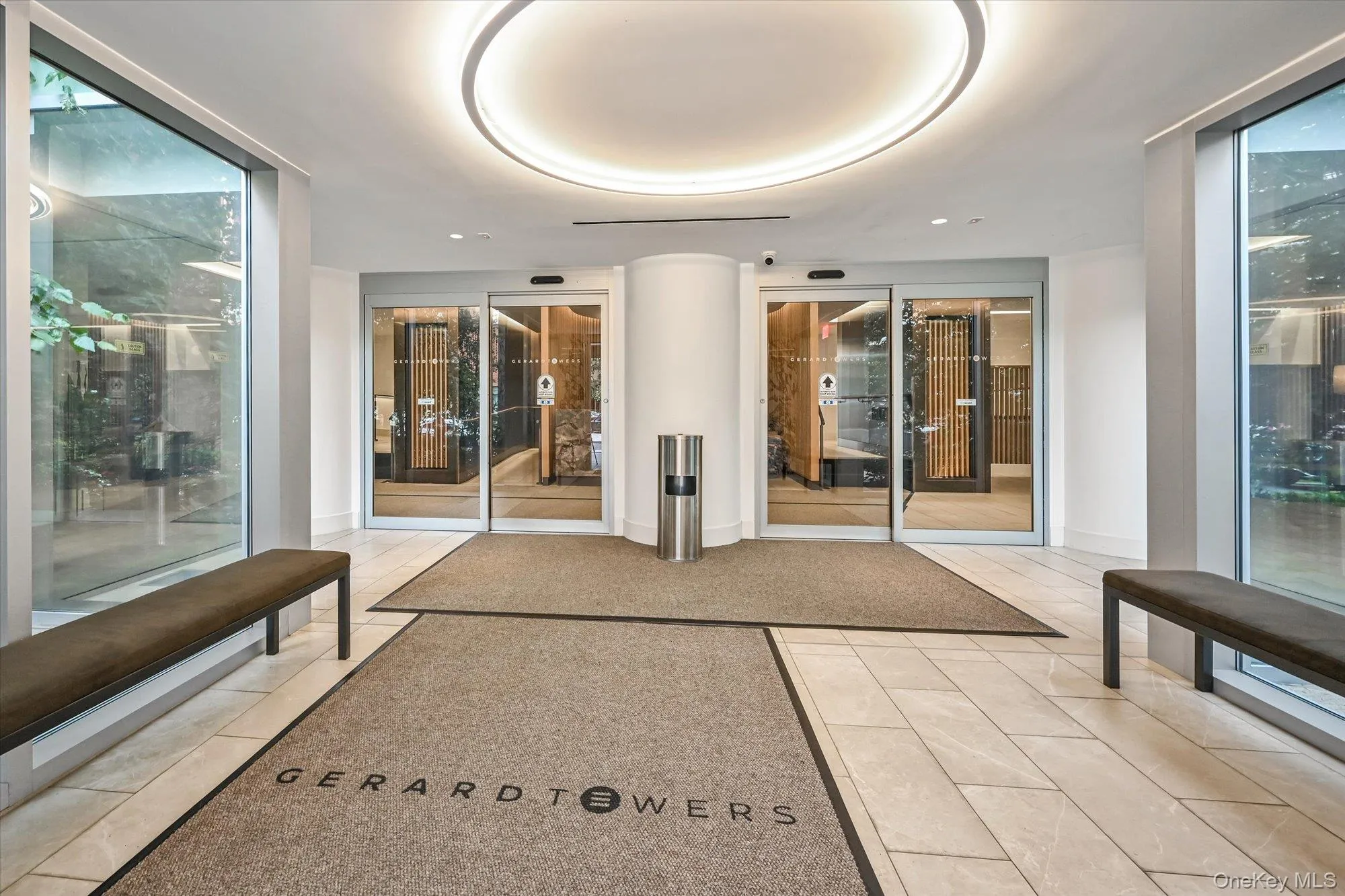 Lobby entrance with automatic sliding glass doors, large format tile flooring, and recessed circular lighting Lobby entrance with automatic sliding glass doors, large format tile flooring, and recessed circular lighting