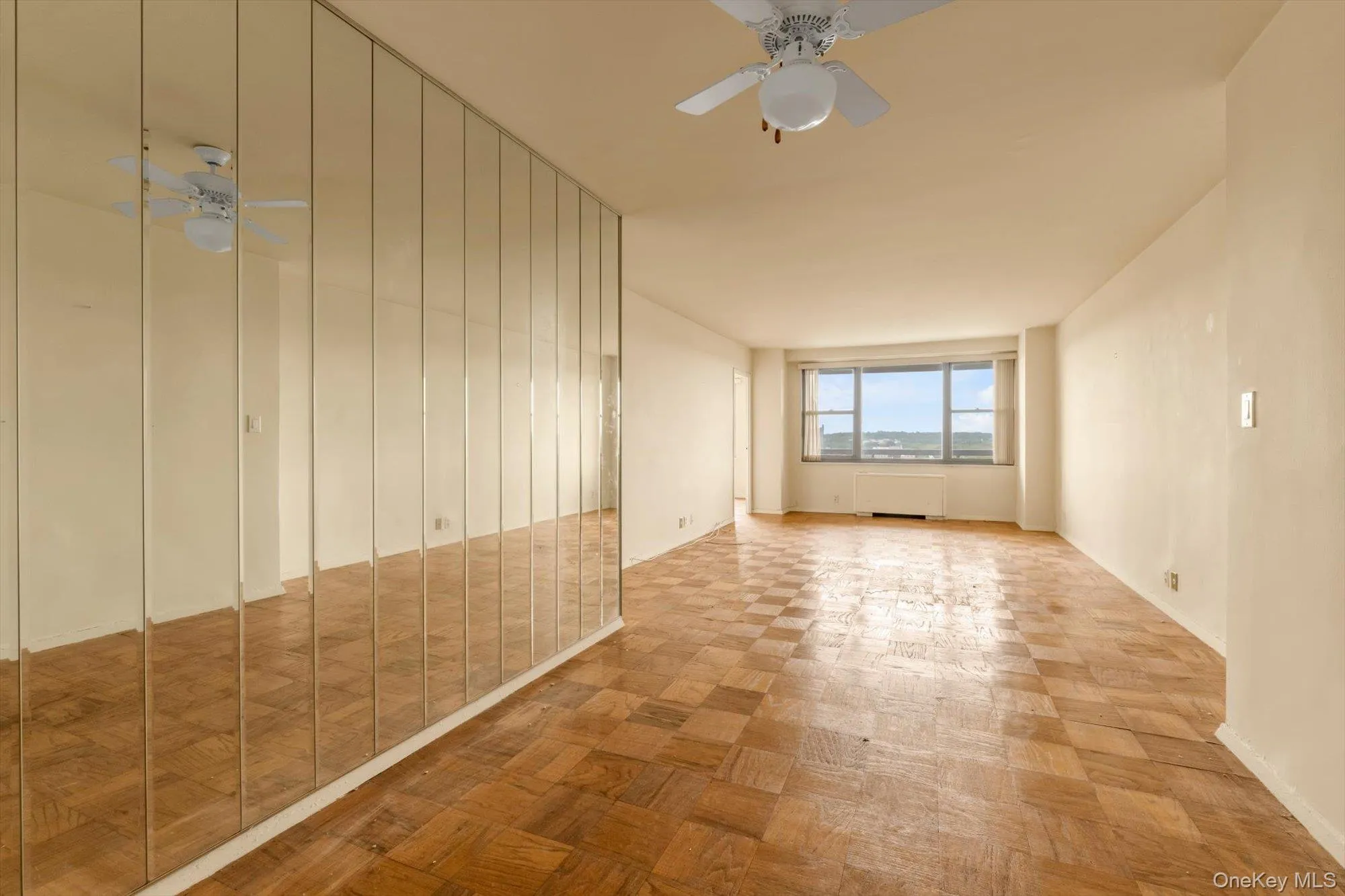 Parquet wood flooring, a window offering scenic surroundings, a ceiling fan fixture, and a mirrored wall Parquet wood flooring, a window offering scenic surroundings, a ceiling fan fixture, and a mirrored wall