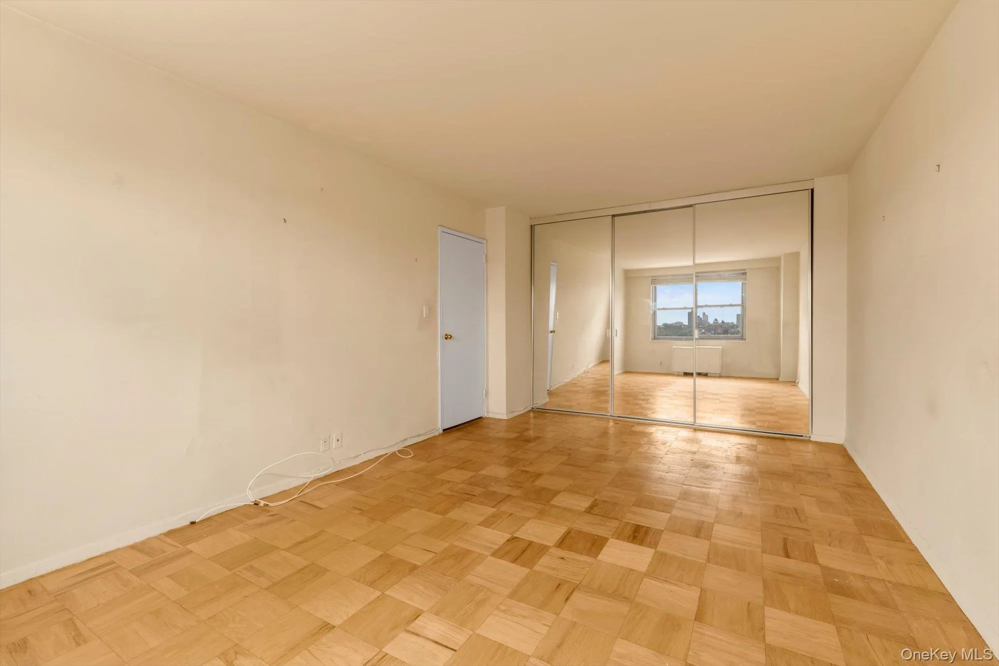 Parquet wood flooring throughout, mirrored wardrobe doors, and a window with a cityscape background Parquet wood flooring throughout, mirrored wardrobe doors, and a window with a cityscape background