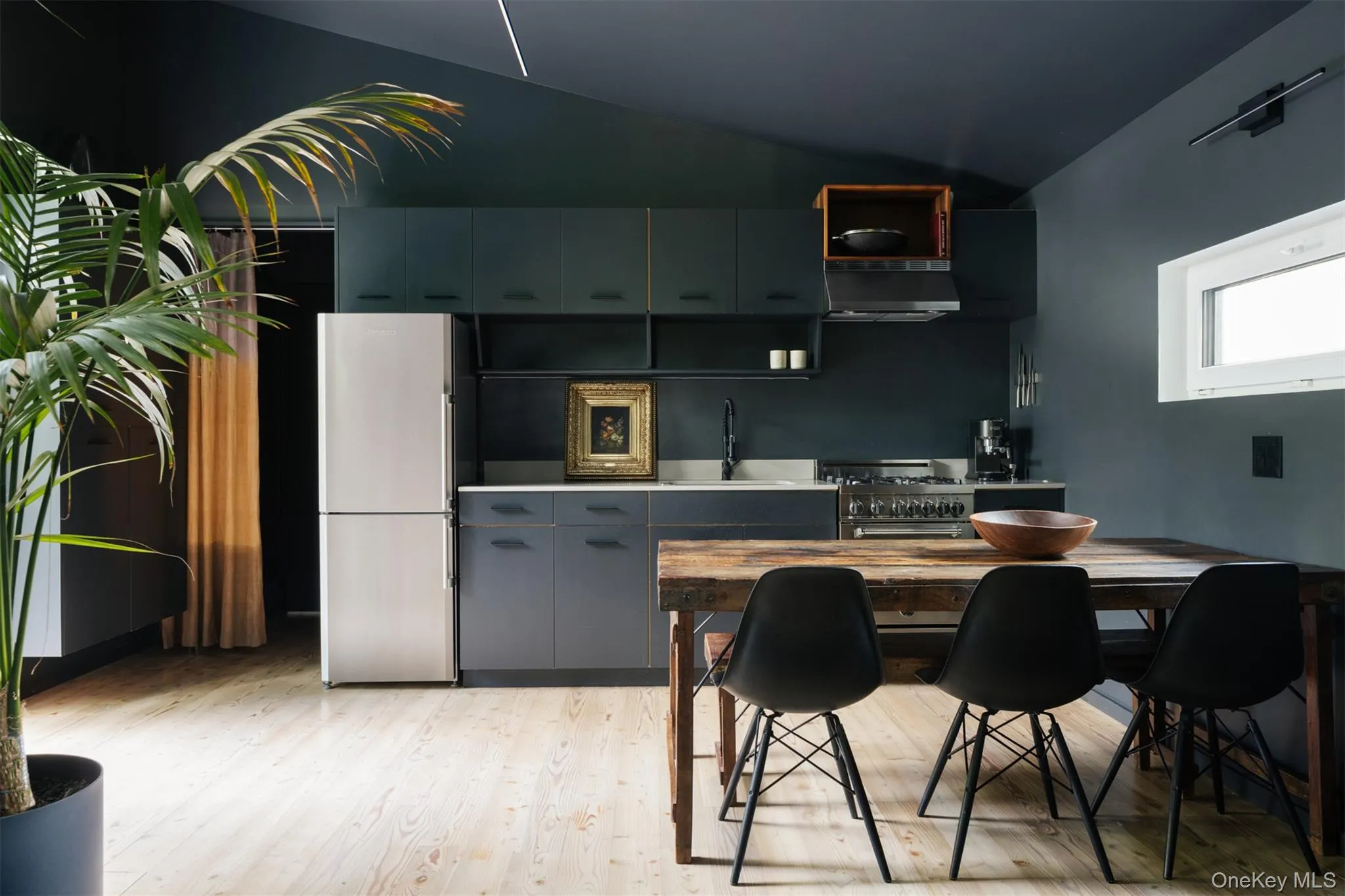 Kitchen with stainless steel appliances, light wood-type flooring, under cabinet range hood, modern cabinets, and light countertops Kitchen with stainless steel appliances, light wood-type flooring, under cabinet range hood, modern cabinets, and light countertops