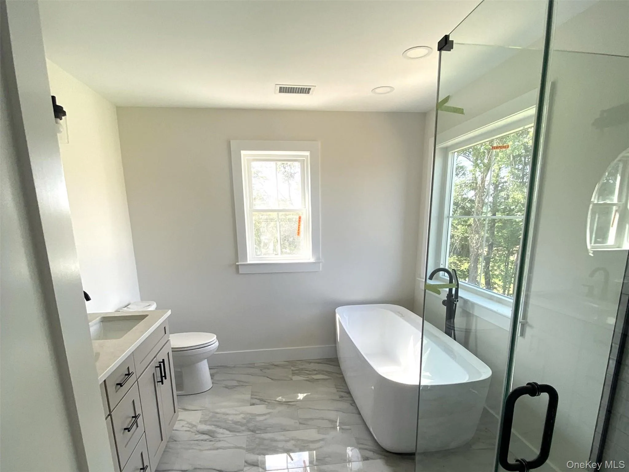 Bathed in natural light, the primary bath offers a serene retreat featuring a freestanding soaking tub, spacious glass-enclosed shower, dual vanity, and elegant finishes designed for both comfort and everyday luxury. Bathed in natural light, the primary bath offers a serene retreat featuring a freestanding soaking tub, spacious glass-enclosed shower, dual vanity, and elegant finishes designed for both comfort and everyday luxury.