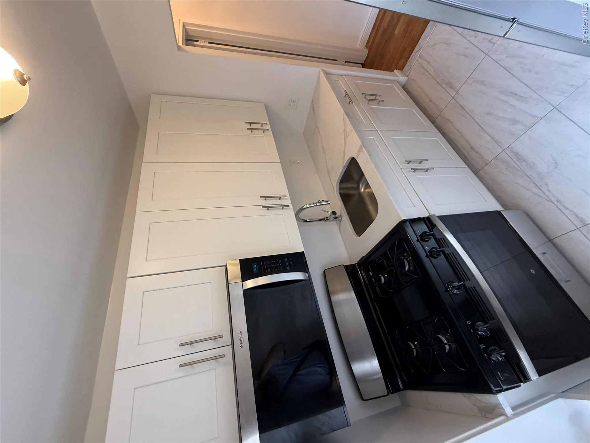 Kitchen featuring white shaker-style cabinetry, stainless steel appliances, and a polished stainless steel sink Kitchen featuring white shaker-style cabinetry, stainless steel appliances, and a polished stainless steel sink