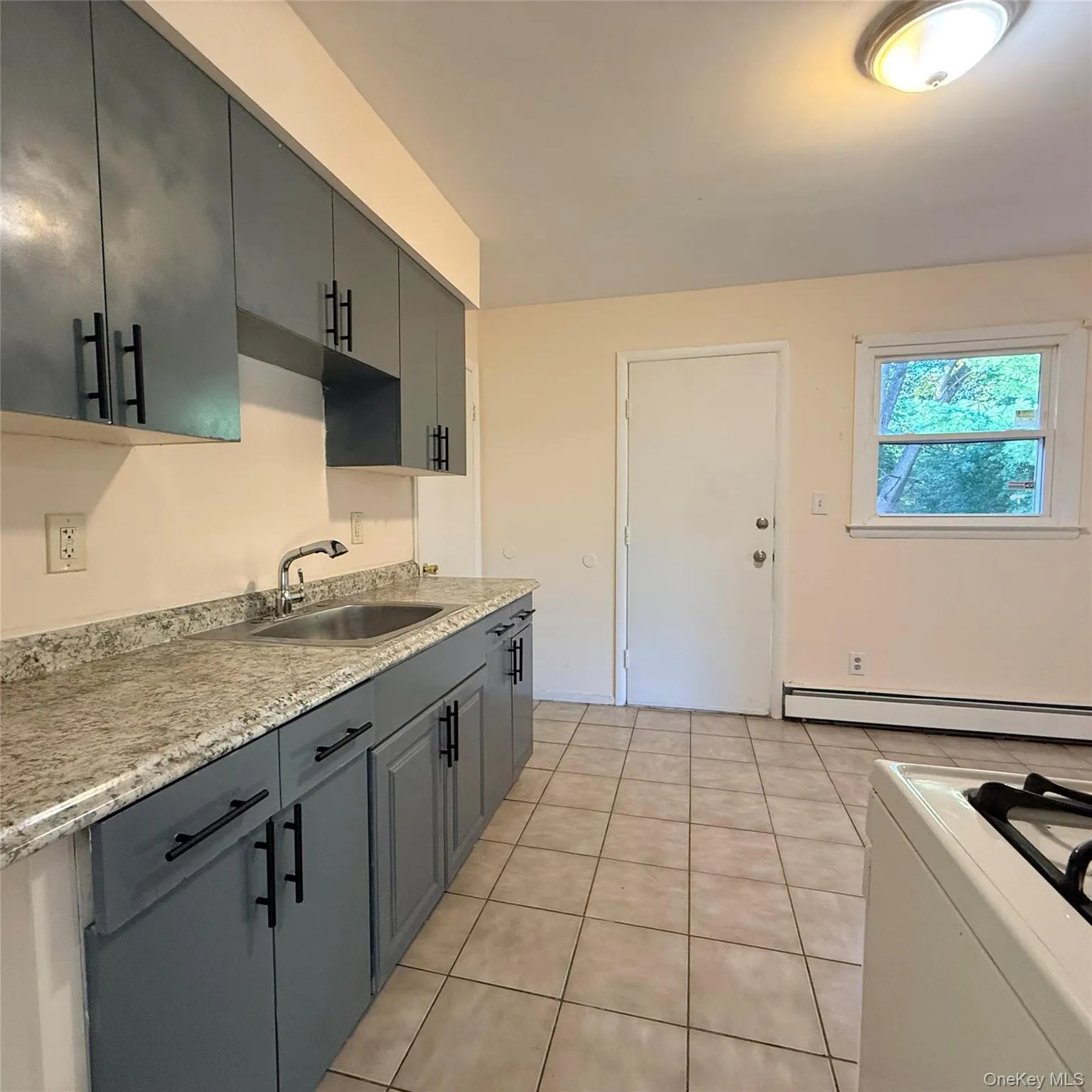 Kitchen featuring shaker-style cabinetry, granite-finish countertops, and a stainless steel sink Kitchen featuring shaker-style cabinetry, granite-finish countertops, and a stainless steel sink