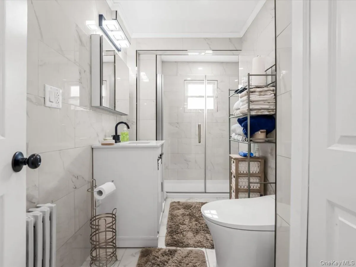 Updated full bathroom featuring a modern vanity, glass-enclosed shower, and sleek tiled finishes. Updated full bathroom featuring a modern vanity, glass-enclosed shower, and sleek tiled finishes.