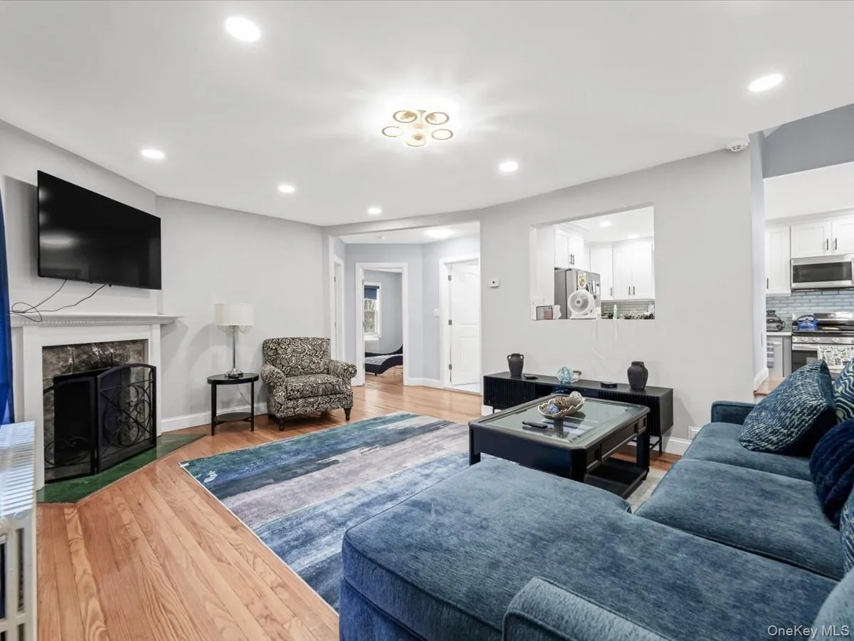 Hardwood flooring, recessed lighting, and a fireplace with a decorative screen Hardwood flooring, recessed lighting, and a fireplace with a decorative screen