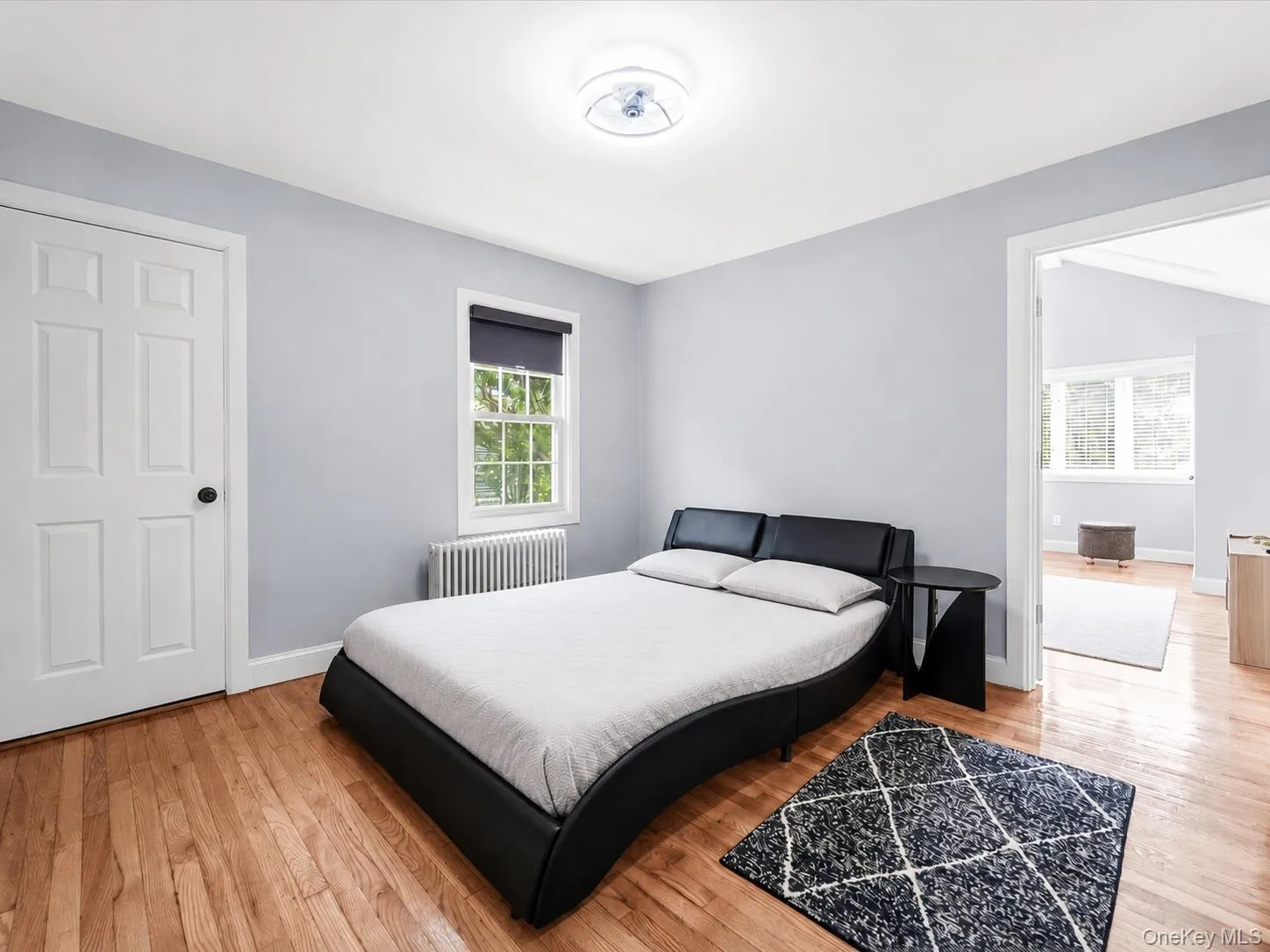 Comfortable bedroom featuring hardwood floors, ample natural light, and radiator heating. Comfortable bedroom featuring hardwood floors, ample natural light, and radiator heating.