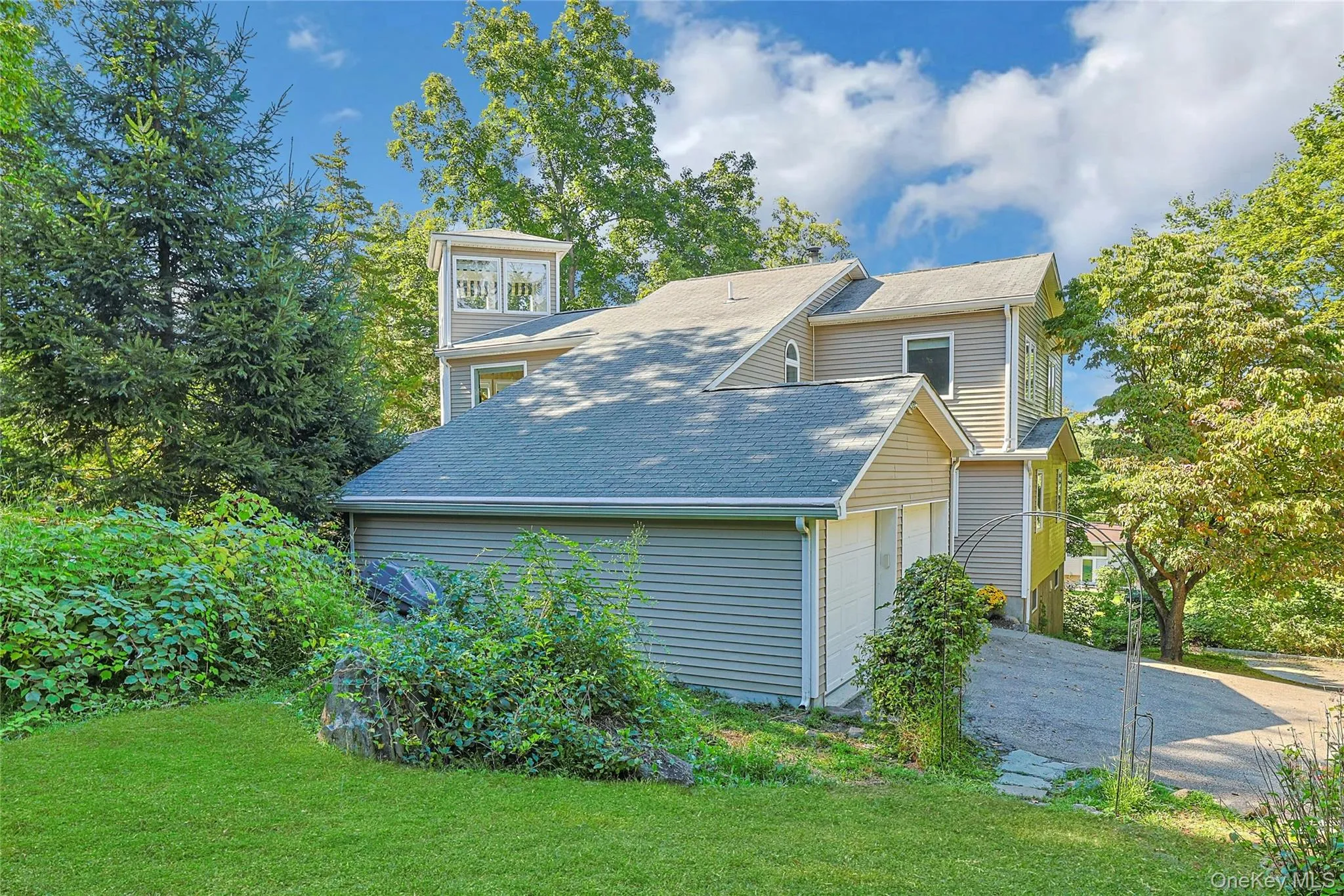 Side view of the home highlights the garage and ample parking area, offering both convenience and functionality. Side view of the home highlights the garage and ample parking area, offering both convenience and functionality.