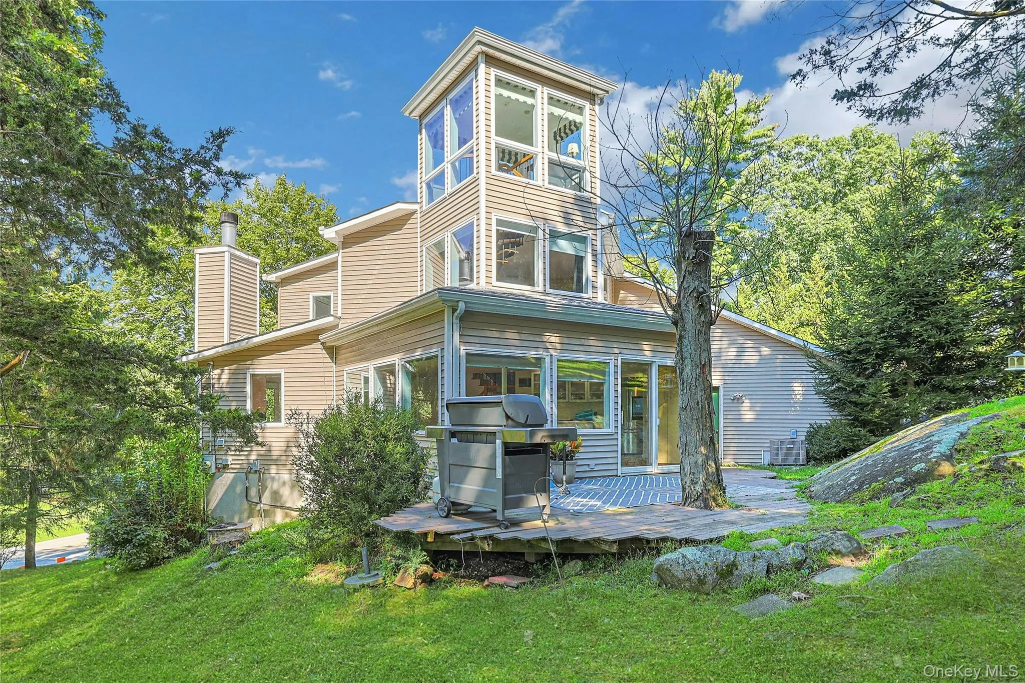 Rear view of the home showcases its beautiful setting and distinctive design, including the charming “Crow’s Nest” above. Rear view of the home showcases its beautiful setting and distinctive design, including the charming “Crow’s Nest” above.