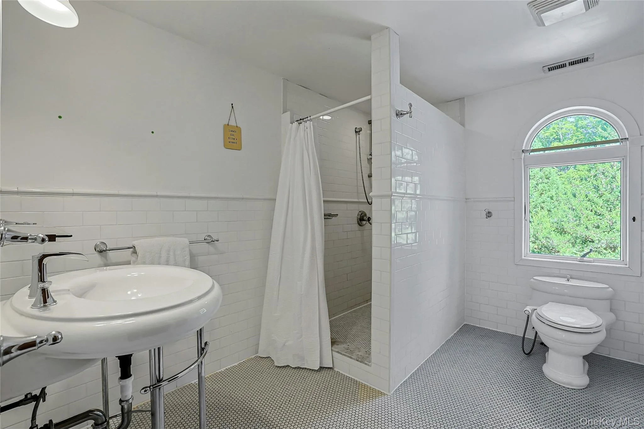 Large primary bathroom with crisp white finishes and an oversized window that fills the space with natural light. Large primary bathroom with crisp white finishes and an oversized window that fills the space with natural light.