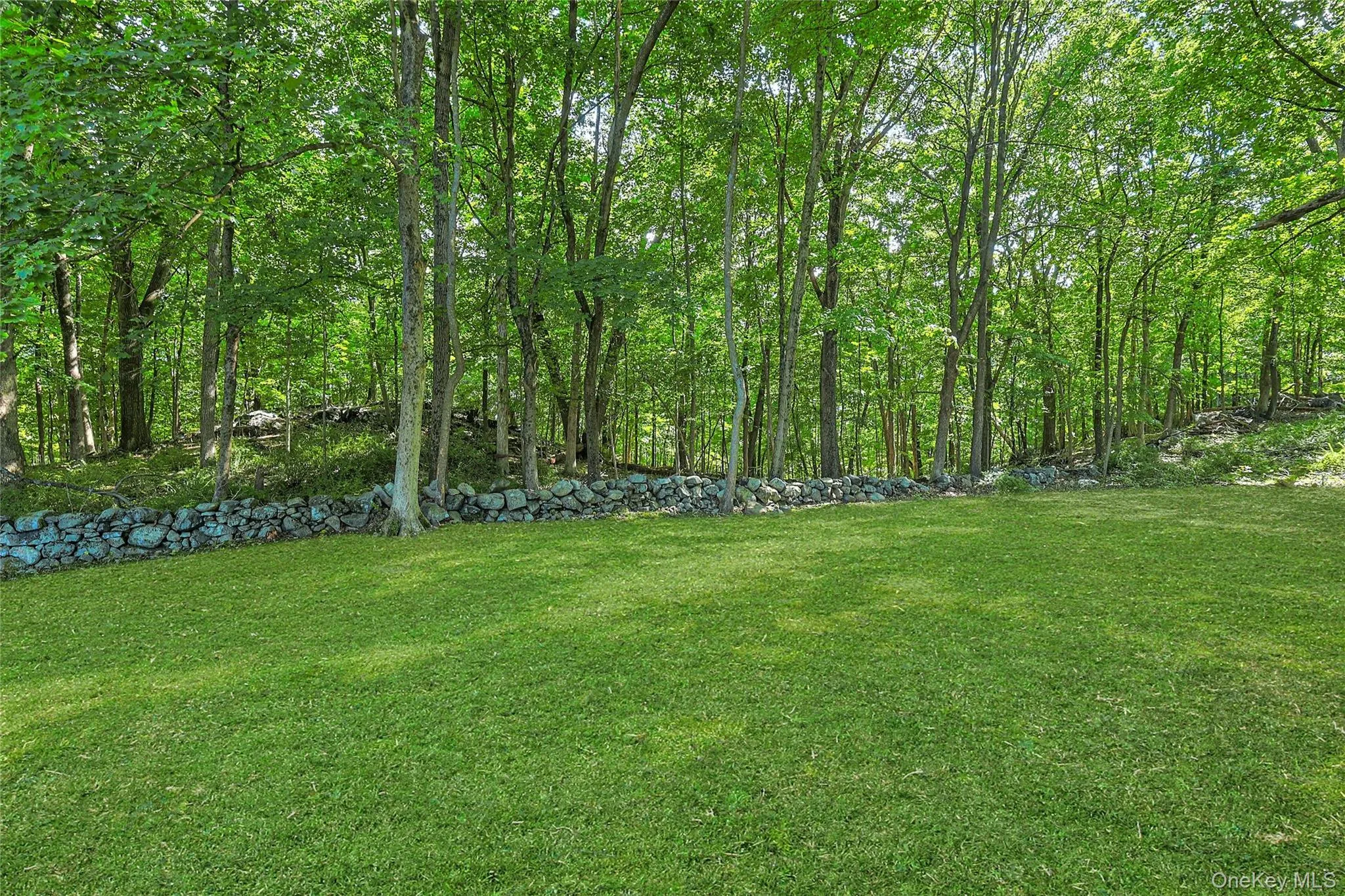 A classic stone wall borders the rear of the property, which adjoins more than 100 acres of protected forest preserve with scenic trails. A classic stone wall borders the rear of the property, which adjoins more than 100 acres of protected forest preserve with scenic trails.