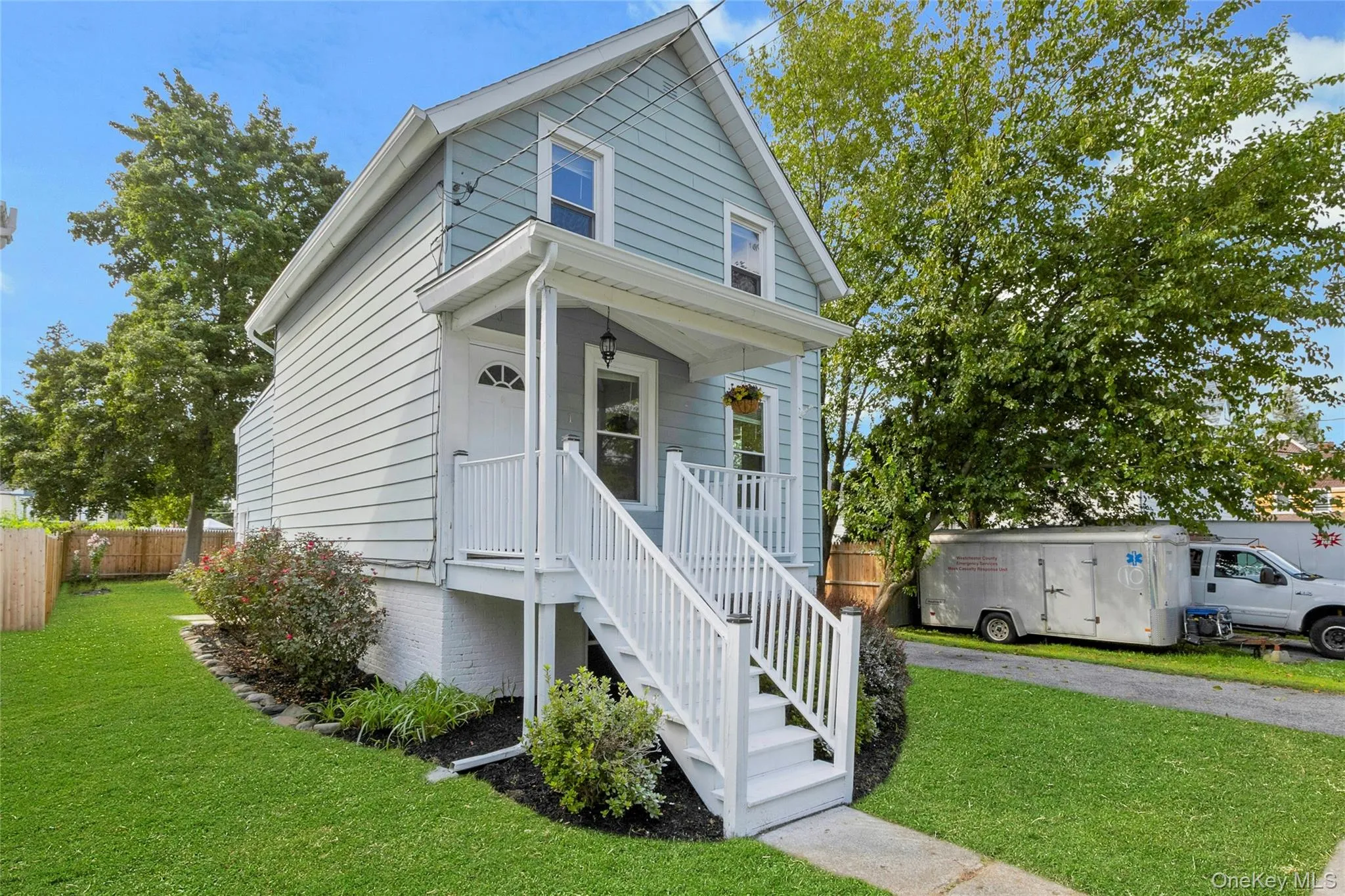 Light blue siding exterior with a covered front porch featuring white railings, a concrete walkway, and a manicured lawn. Light blue siding exterior with a covered front porch featuring white railings, a concrete walkway, and a manicured lawn.